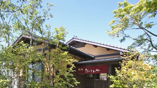 御宿だいこんやの外観。木々に囲まれた和風の建物と、屋号の入ったのれん
